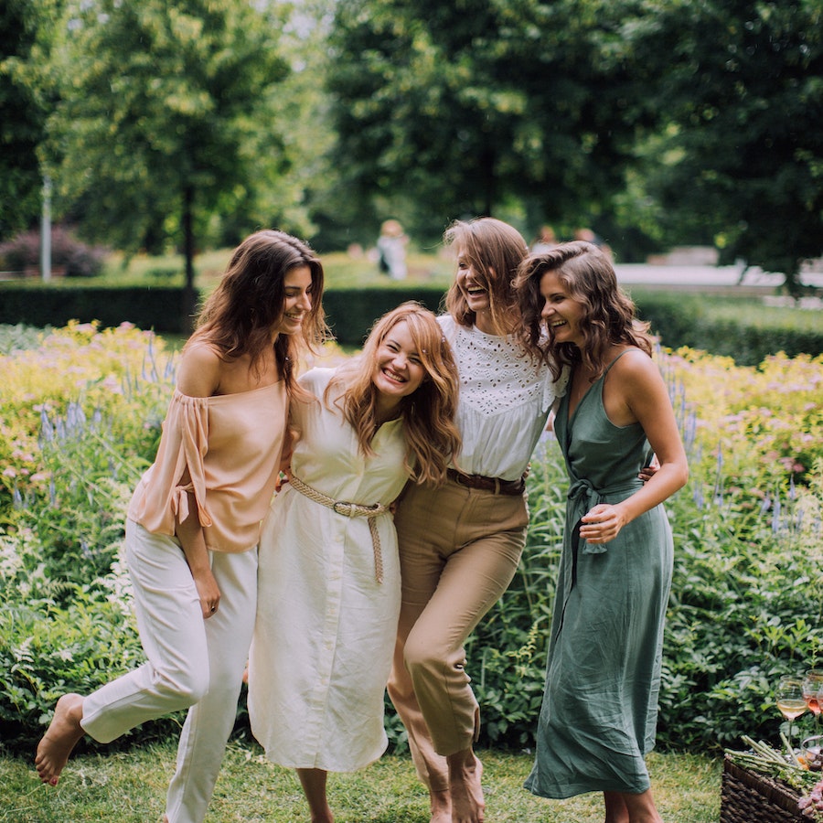 Group of happy women standing in front of a garden