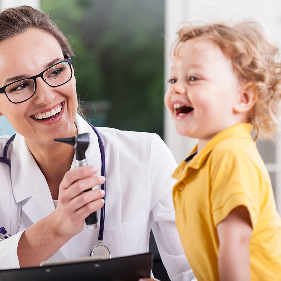 woman pediatrician with otoscope smiles at laughing child