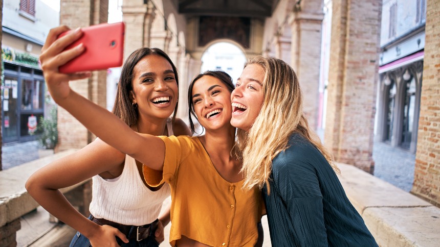 three women posing and laughing while taking a selfie