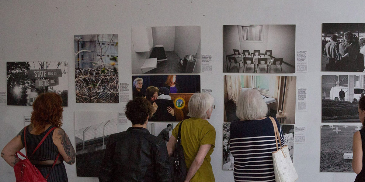 People looking at art on a white wall.