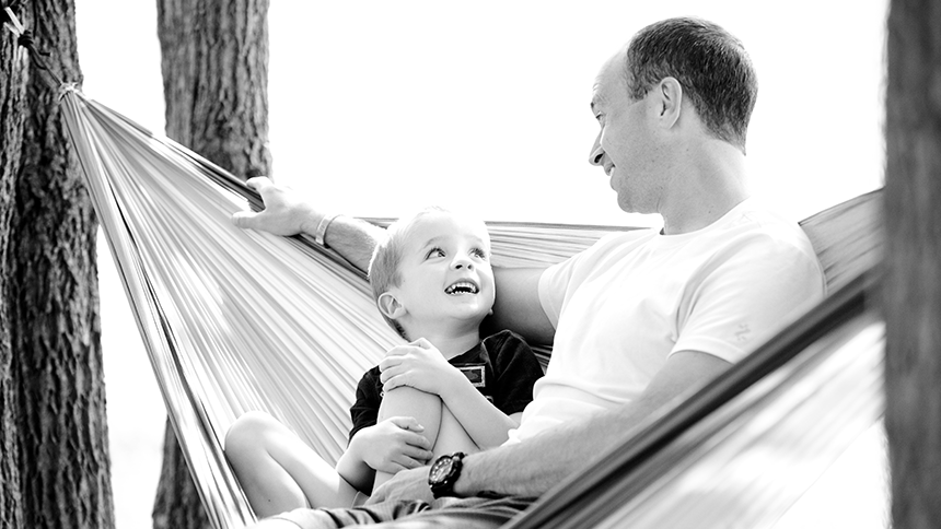 A father and son on a hammock. The photo is in black and white.
