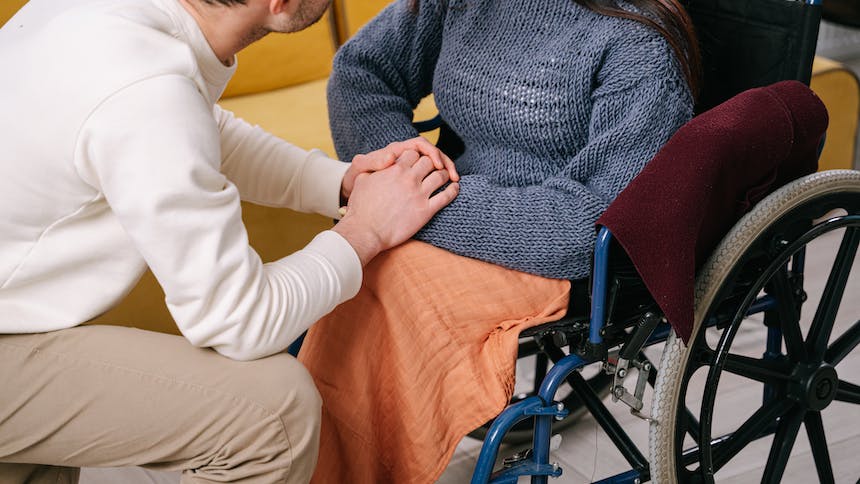 Caregiver holding woman's hand in wheel chair 