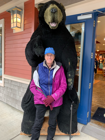 Connie Wilson in Ketchikan, Alaska standing in front of a large brown bear statue. 