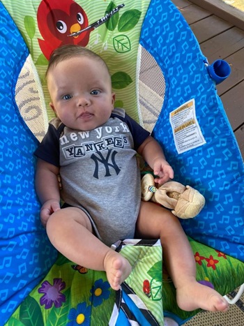 Chunky baby sits in chair with Yankees outfit on