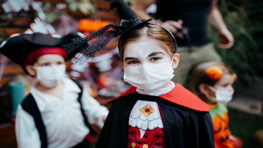 A child dressed as a vampire wears a mask for Halloween safety.