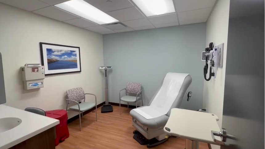 Patient room featuring chairs, a weight scale, sink, medical waste disposal, blood pressure cuff and thermometer.