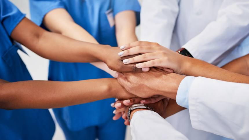 A diverse group of healthcare providers with their hands in a circle.