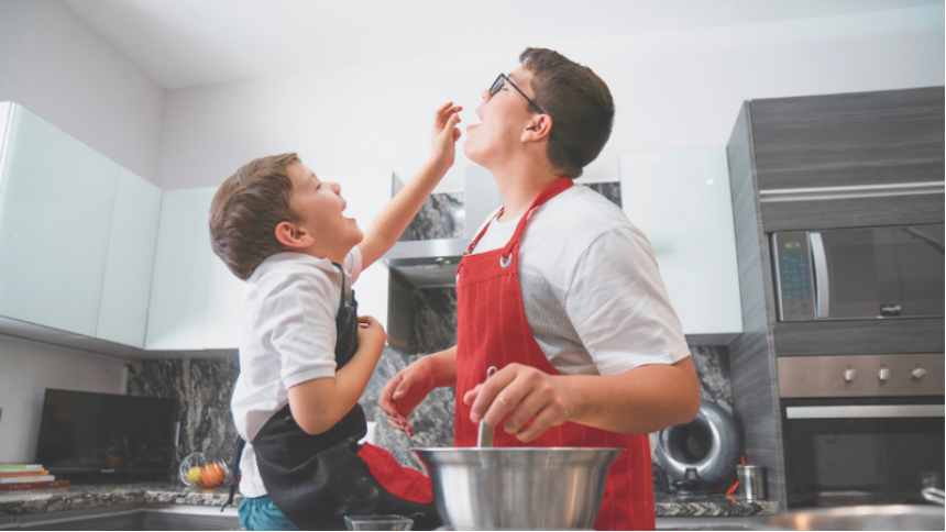 Young dad and son cooking over a stove. Some fall foods can help or trigger heartburn.