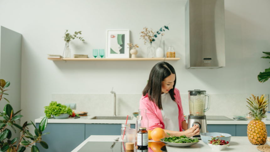 Young woman blending a smoothie with anti-inflammatory foods in her kitchen.