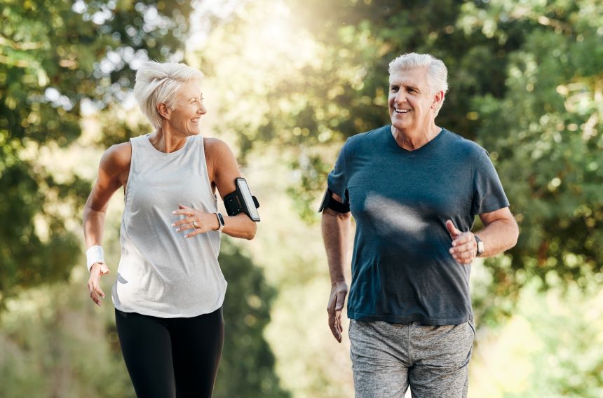 Husband and wife in their 60s running outside in the woods in the summer