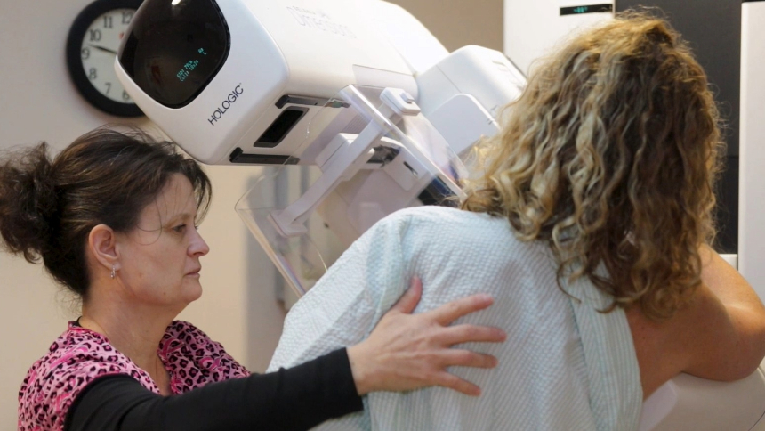 Mammogram technologist positions woman for a screening. 