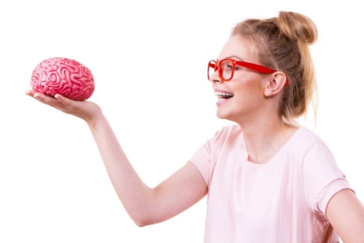 Young woman laughing and holding a model of a pink brain