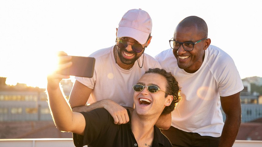 Three men taking a selfie while smiling outside at dusk