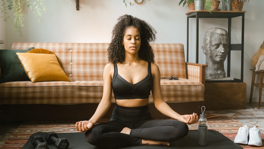 Woman in black activewear meditating indoors