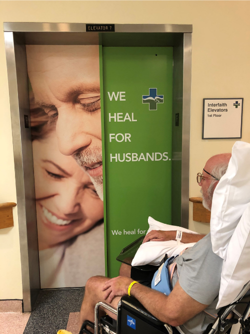 Mike Foster sitting in a wheelchair in front of an elevator in a hospital in Florida after having a stroke.