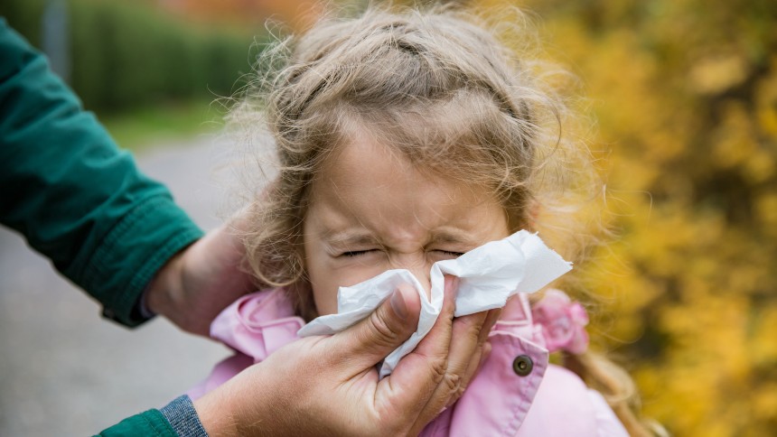 A child blows her nose into a tissue.