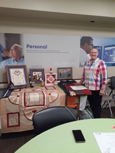 Vassar Brothers Medical Center breast cancer patient Linda Deserto standing next to a table of quilts she made at a Cancer Survivors Day event. 