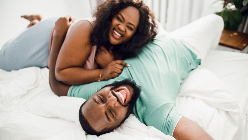 A man and a woman laughing on a bed.