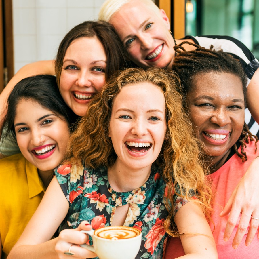 Group of smiling, diverse women drinking a cappuccino 