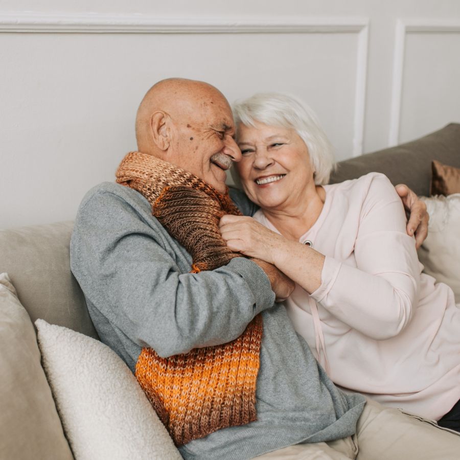 Elderly couple on couch hugging