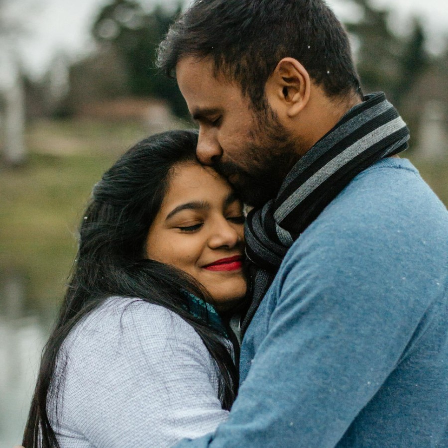 Man in blue kissing woman on the forehead