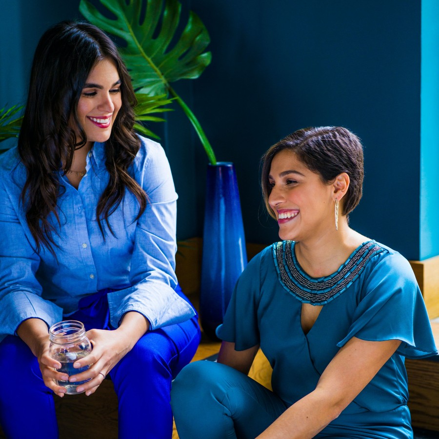 Two women sitting wearing blue