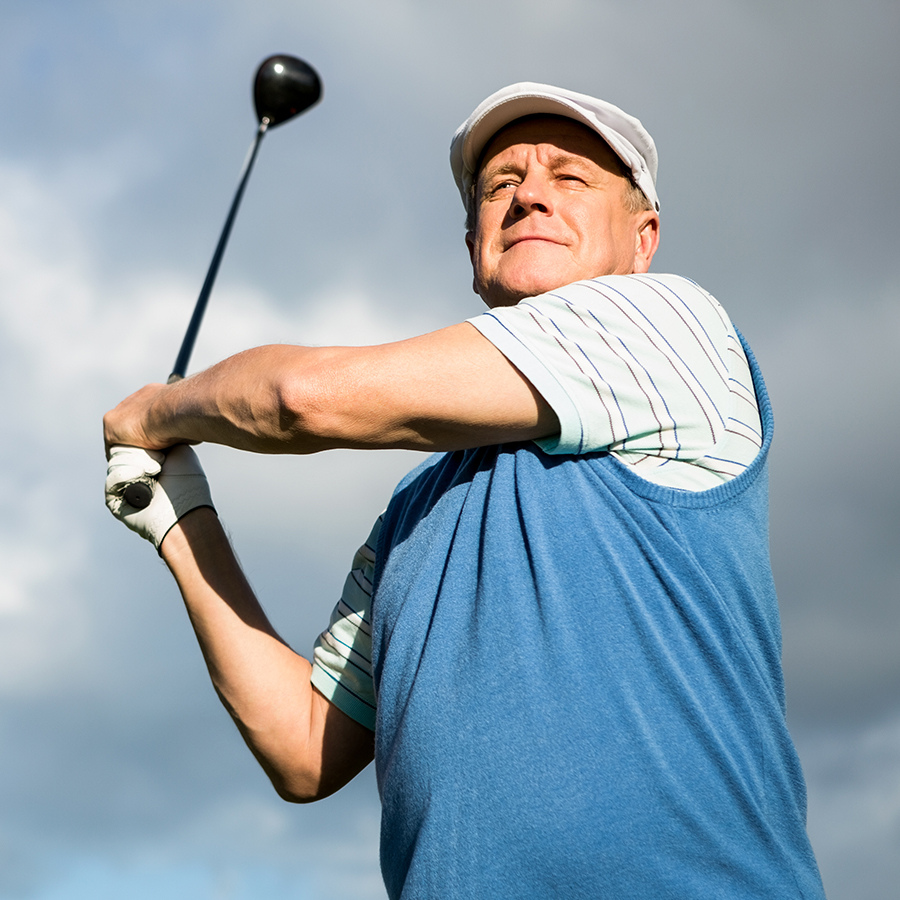 Golfer standing and swinging his club on a sunny day at the golf course