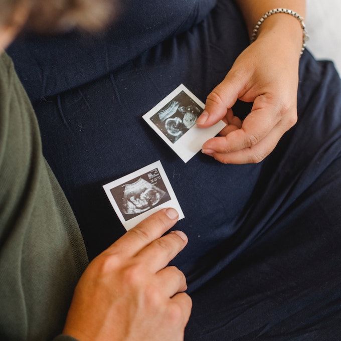 Pregnant couple holding sonogram images