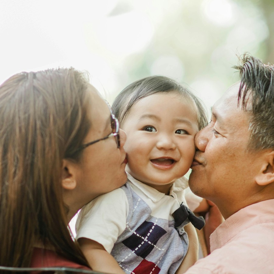 Asian couple kissing happy baby