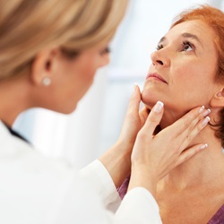 woman doctor checks female patient's neck glands