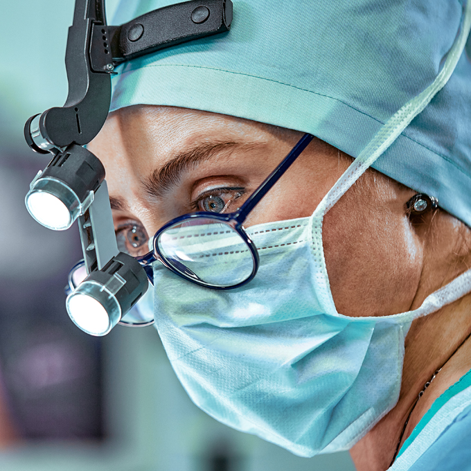 close up of female surgeon with medical binoculars