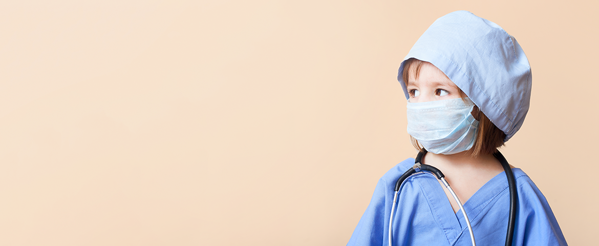coung child wearing stethoscope, scrubs, and mask