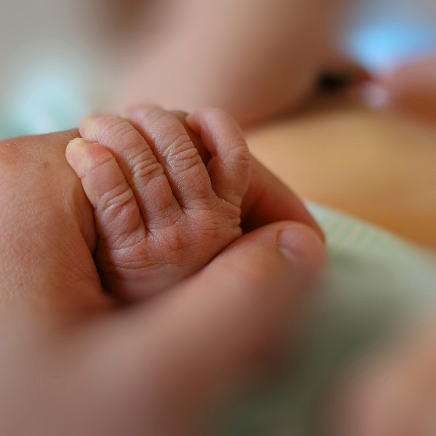 mothers holds hand of newborn
