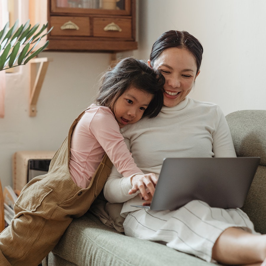 Happy mother using laptop with daughter