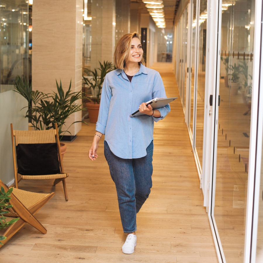 Woman in blue dress shirt walking down the hallway