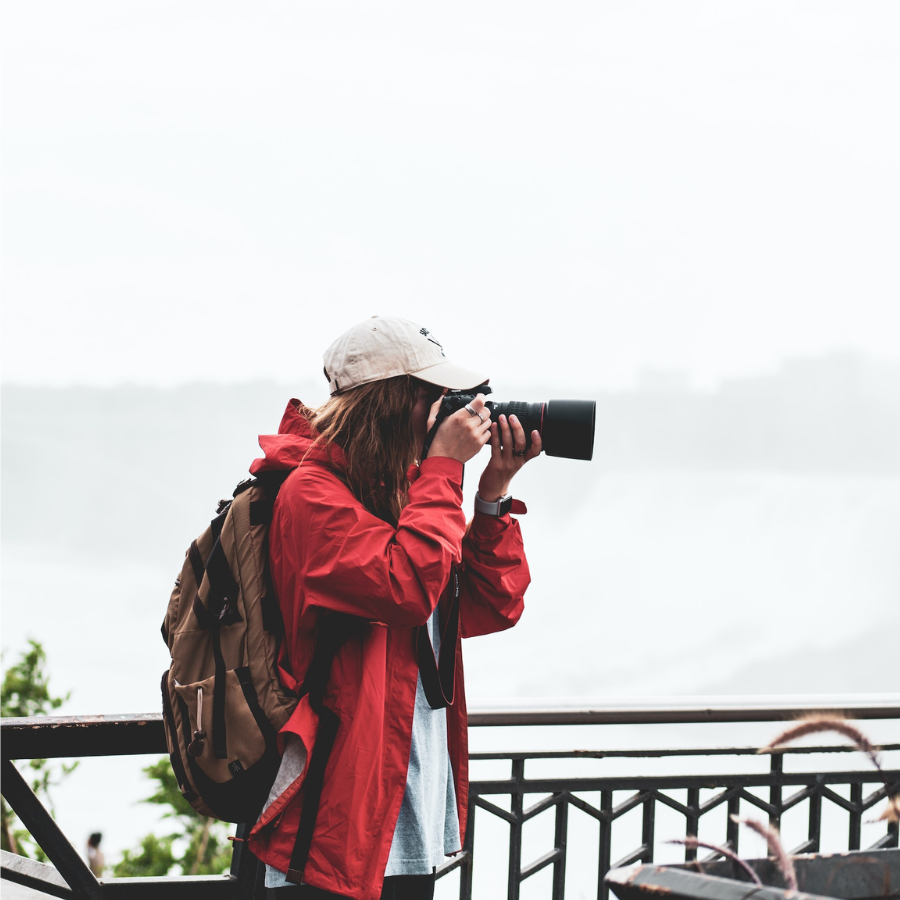 Woman in red jacket holding black camera