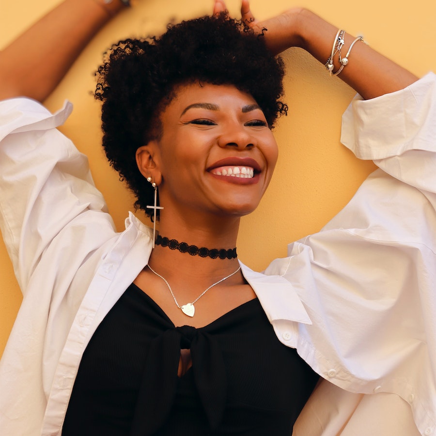 Woman smiling in a white shirt with yellow background