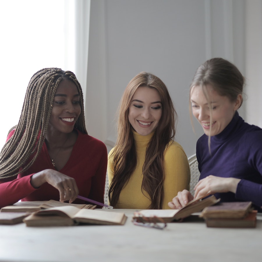 Young women sitting together with books at a table