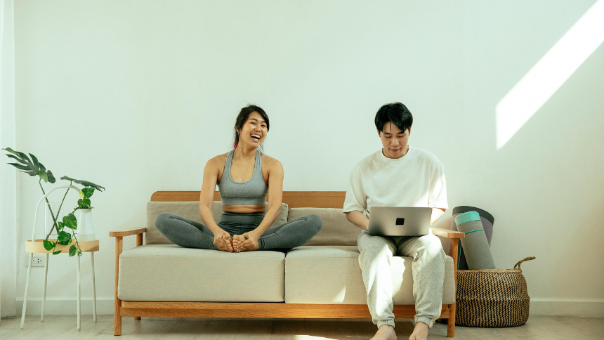 A woman and man sitting on a couch, the woman is in athletic attire and the man is in casual attire.