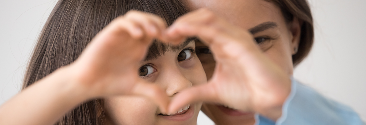 girl looking through heart made with her hands