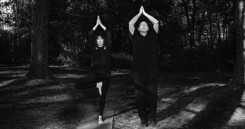 Michael and Gloria doing yoga poses outdoors.