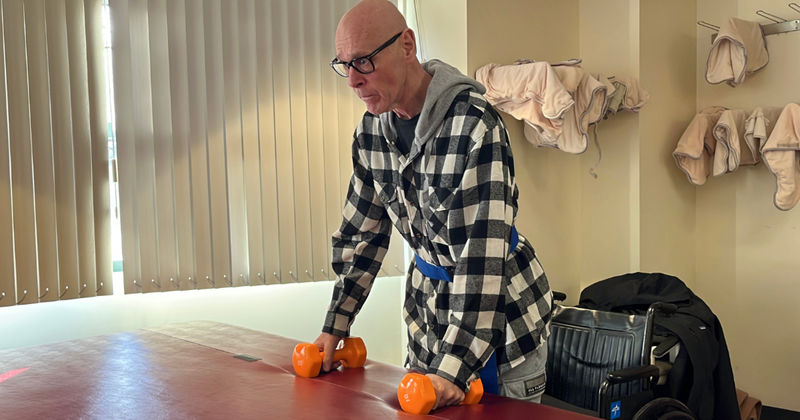 Michael holding onto 10lb dumbbells in each hand, about to practice occupational therapy exercises.