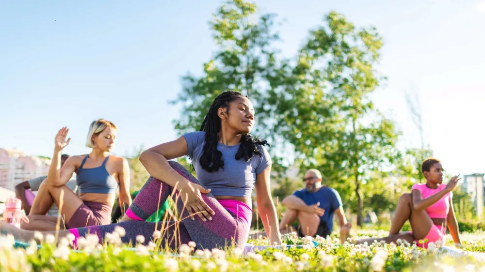 Multiracial adults practicing yoga outside.