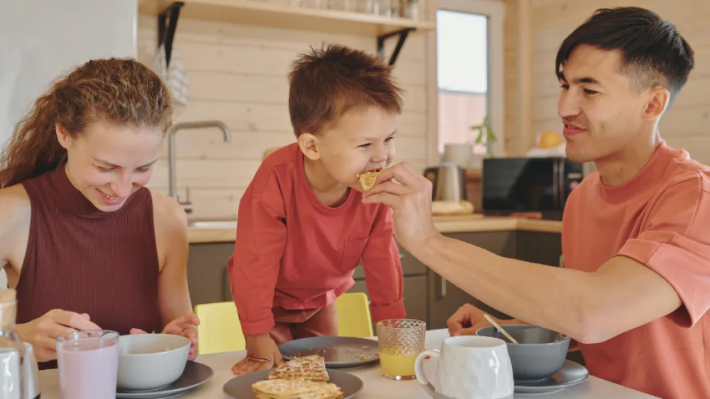 A family eating breakfast at the kitchen table