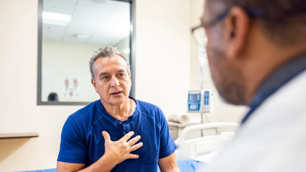 Senior man talks with his doctor in a medical office about his upper gastrointestinal health and risk of Parkinson’s disease.