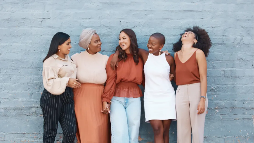 Multi-ethic women of different ages standing and laughing together.