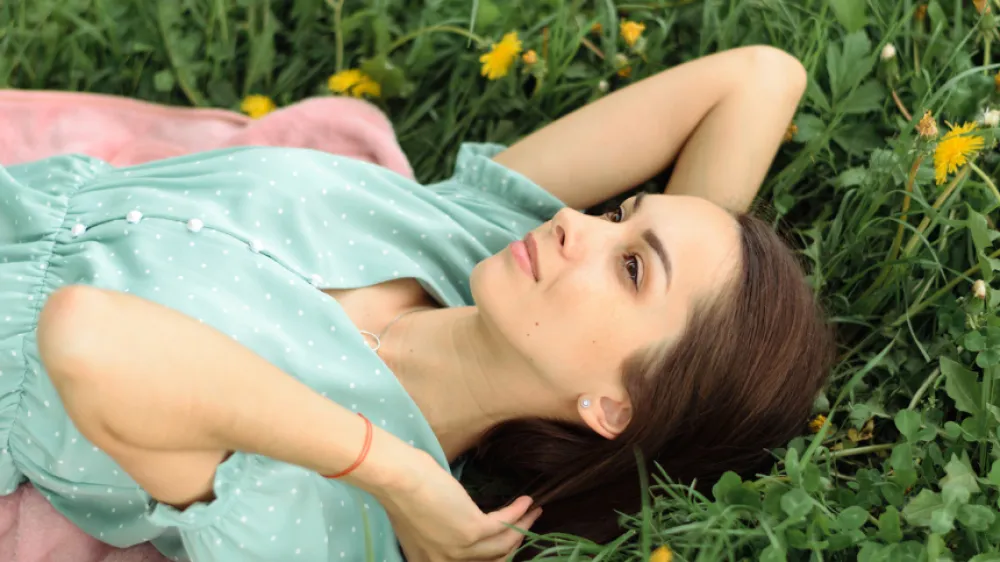 Portrait of a beautiful happy young woman lying on the grass on a summer day.