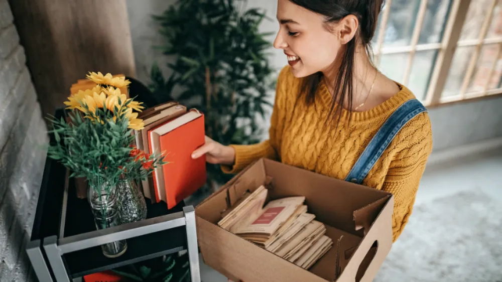 A young woman organizing a bookshelf in her house, so her brain is healthy and free of clutter.