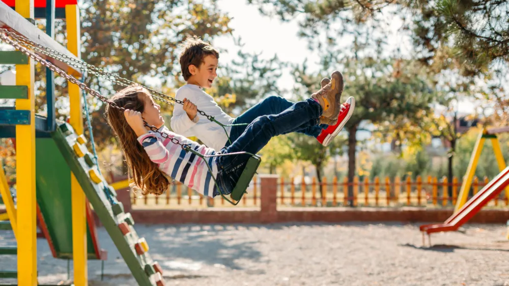 Happy children having fun swinging and enjoying