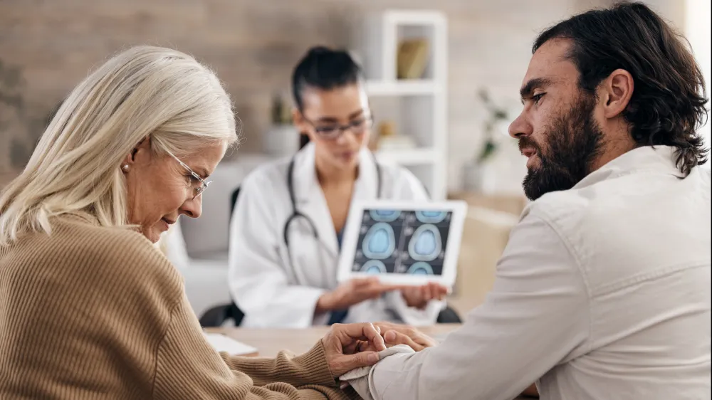A older woman with her adult son consulting with a neurosurgeon about a brain cancer diagnosis.